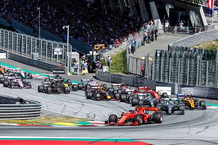 formula one cars racing at the Austrian GP with a large crowd in the back ground