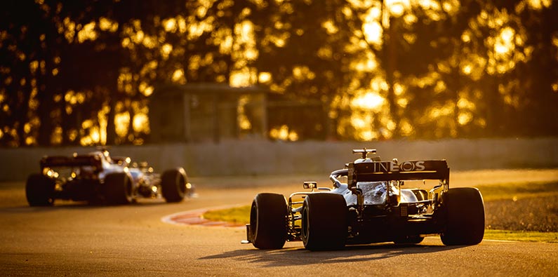 formula one cars racing at dusk time